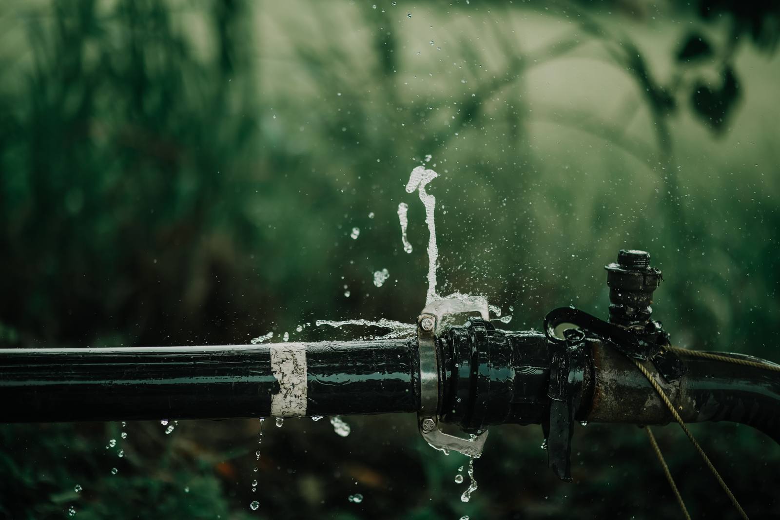 A burst water line spraying — the kind of active leak that calls for emergency plumbing service