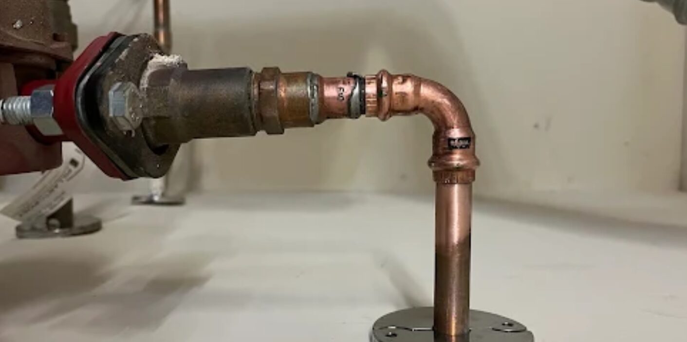 Close-up of copper pipe entering wall with signs of sealant used in a damaged plumbing system