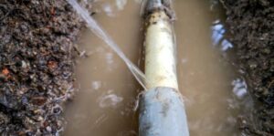 Broken underground pipe leaking into muddy soil