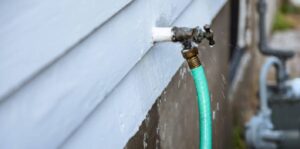 Leaking outdoor hose bib connected to green garden hose