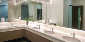 A clean, brightly lit commercial bathroom with multiple sinks and large mirrors, representing the high-quality office plumbing solutions from a trusted company.