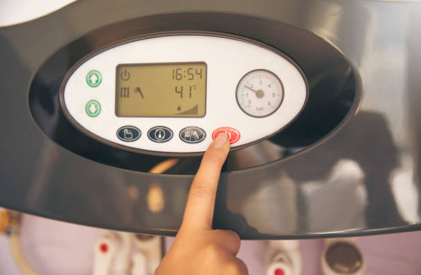 Hand adjusting the digital controls of a modern Tankless water heater, showing temperature and settings for efficient hot water.