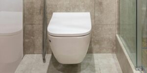A modern, high-efficiency toilet in a tiled bathroom, representing new installation and professional replacement of fixtures with Common Toilet Problems.