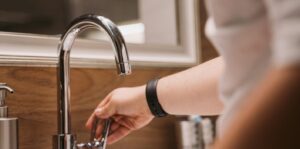A homeowner testing a bathroom faucet during a self-check for a leak detection check.