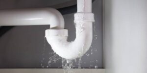 A water droplet falling from a modern chrome faucet, causing a constant dripping sound.