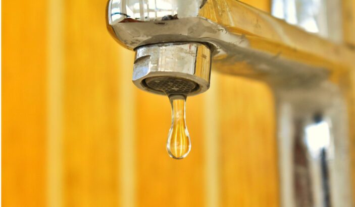 Close up of a leaking chrome faucet dripping water in a Knoxville home, highlighting the importance of early leak detection.