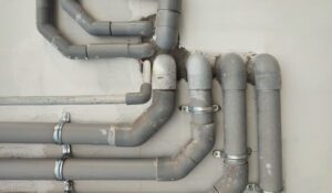 Complex network of grey PVC plumbing pipes secured to an indoor wall by a professional plumber in Knoxville, Tennessee.