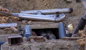 An open excavation trench showing underground main water and sewer lines undergoing professional repair in Knoxville, Tennessee.
