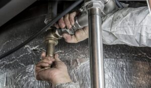 Licensed emergency plumber tightening a metal joint during a water line repair service.