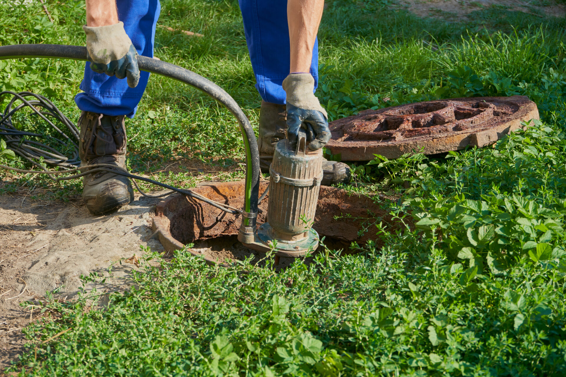 Plumber removing a submersible sump pump from an outdoor pit for inspection and maintenance in Knoxville