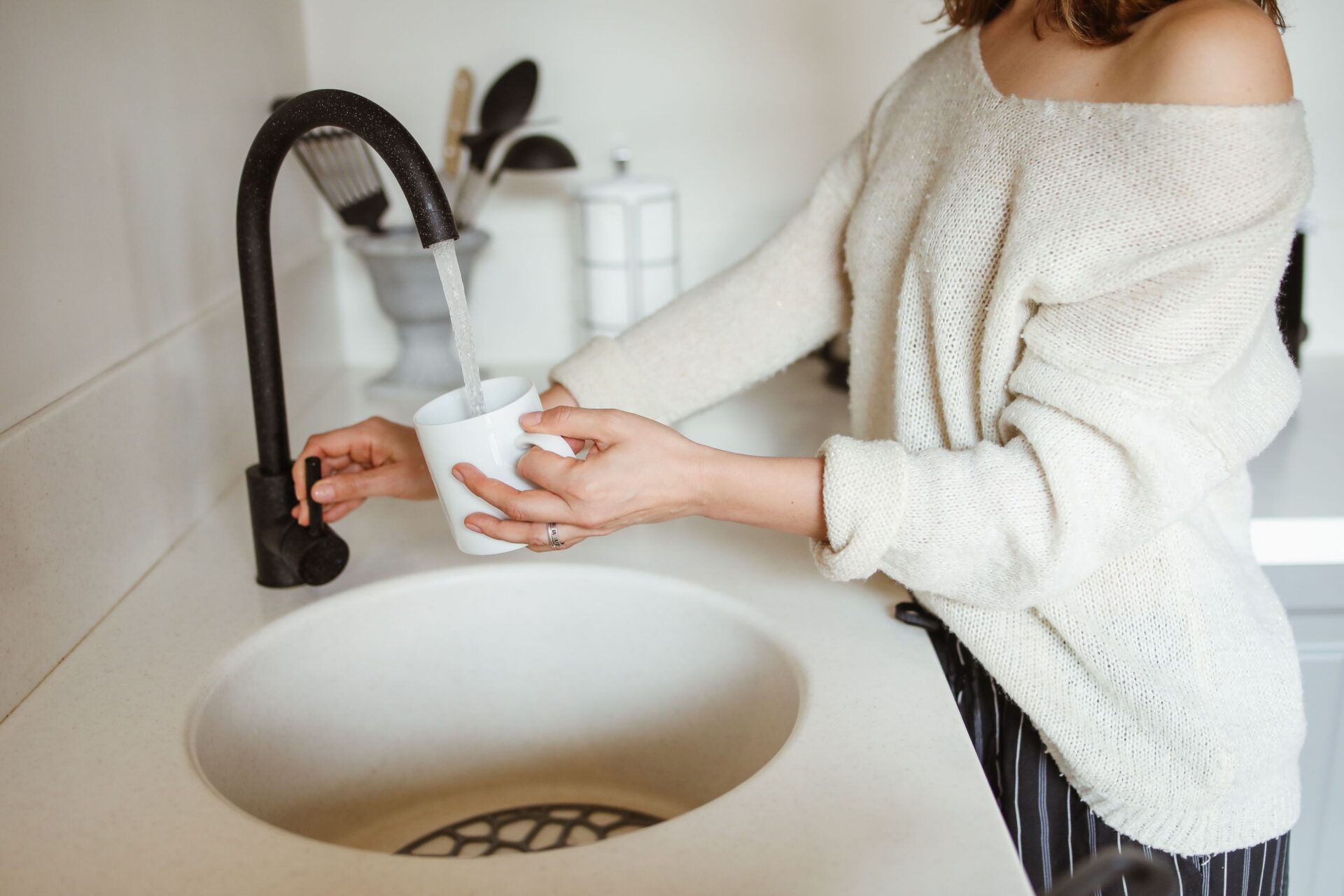 Homeowner filling a mug with water from a kitchen faucet in a Knoxville home