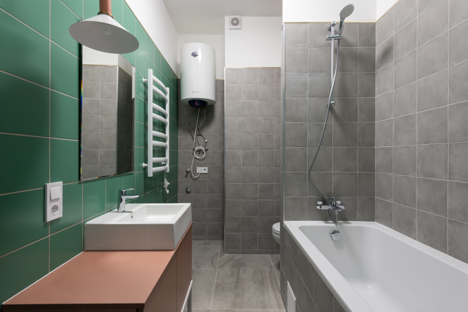 Wall-mounted water heater unit installed in a home bathroom near the shower and bathtub