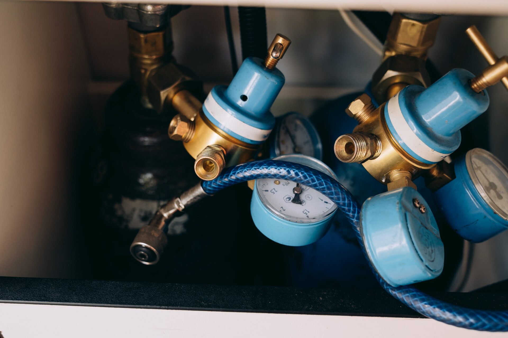 Close-up of water heater valves and a pressure gauge during a maintenance inspection